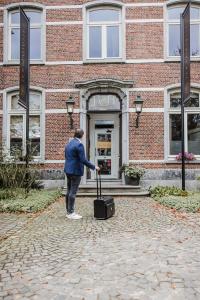 une personne debout devant un bâtiment avec une valise dans l'établissement B&B Roosendaelhof, à Geel