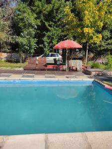 einen Pool mit einem Tisch und einem Sonnenschirm in der Unterkunft aires de montaña in Ciudad Lujan de Cuyo
