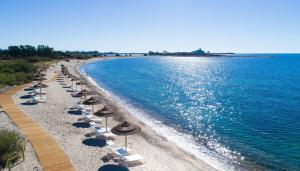 a beach with umbrellas and chairs and the water at Golf & Sea Residence Is Molas in Pula