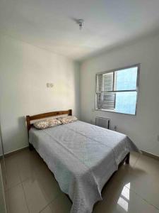 uma cama num quarto branco com uma janela em Apto 50m da praia Gonzaguinha São Vicente Edifício Estrela do Mar em São Vicente