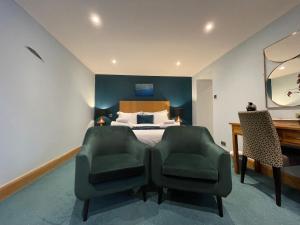 a bedroom with a bed with two chairs and a desk at The Ship Inn - Winner Best Hotel Experience 2024 Visit Scotland in Gatehouse of Fleet