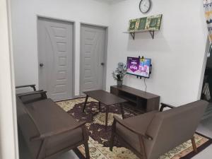 a living room with two chairs and a table and a clock at D'Parking Homestay Klia Sepang Budget Murah in Banting