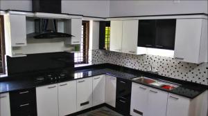 a kitchen with black and white cabinets and a sink at Kayyany's Villa - A Large Family Home in Kanjirapalli