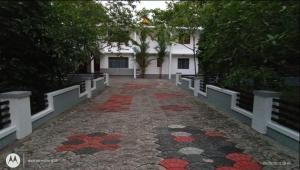 a brick walkway leading to a white building with trees at Kayyany's Villa - A Large Family Home in Kanjirapalli