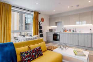 a living room with a yellow couch and a kitchen at Little Gem in Poole