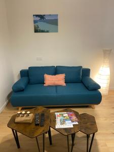 Sofá azul en una sala de estar con 2 mesas en Charmant appartement en Saint-Claude