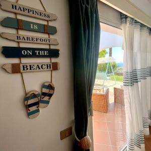 沙姆沙伊赫La Vista Mare Domina Coral Bay的海滩上赤脚的有读幸福的标语的房间