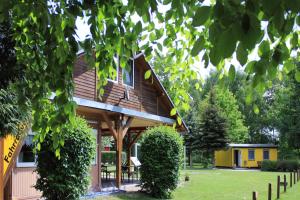 a house with a yellow building in the background at Feriendorf am Flämingbad Bungalow in Coswig