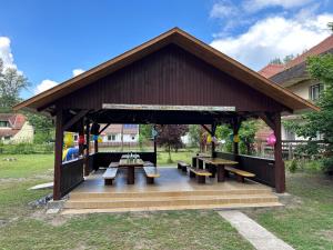 a pavilion with benches and tables in a park at Lakeside Apartmanház Soltvadkert in Soltvadkert