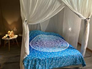 a bed with a blue comforter and a canopy at Kazamwe in Petit-Bourg