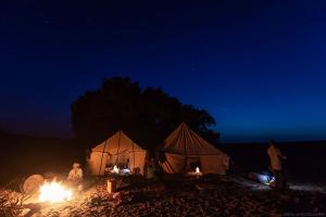 uma tenda com pessoas à volta dela à noite em Bivouac Beauté de Désert em Mhamid