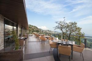 um restaurante com mesas e cadeiras numa varanda em Fortune Resort Grace, Mussoorie - Member ITC's Hotel Group em Mussoorie