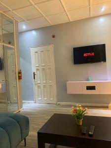 a living room with a couch and a tv on the wall at Teal Snug Open-Plan Studio Unit in Lekki Phase 1-Netflix, Wi-Fi, 24-7 Light, Washer, Kitchen in Lagos
