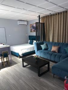 a living room with a blue couch and a bed at Teal Snug Open-Plan Studio Unit in Lekki Phase 1-Netflix, Wi-Fi, 24-7 Light, Washer, Kitchen in Lagos