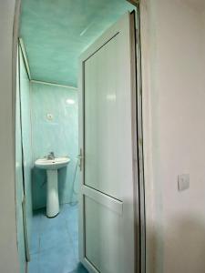 a bathroom with a shower door and a sink at Дом в старом тбилиси in Tbilisi City