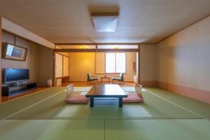 a room with a table and chairs and a television at 層雲閣 in Kamikawa