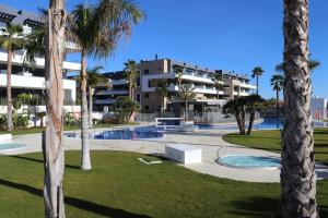 een resort met een zwembad en palmbomen bij 3-bedroom penthouse with private roof terrace and fantastic view in Orihuela