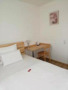 a bedroom with a white bed and a desk at Hotel Hanseatic-garni in Wuppertal