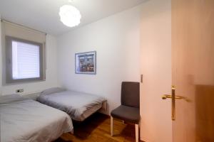 Un dormitorio con dos camas y una silla y una ventana. en Comfy Downtown + Private terrace, en Barcelona