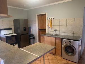 uma cozinha com uma máquina de lavar roupa e uma máquina de lavar roupa em Bougain Villa BnB em Polokwane