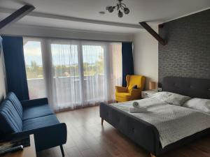 a bedroom with a bed and a couch and a chair at Főnix Badacsony in Badacsonytomaj