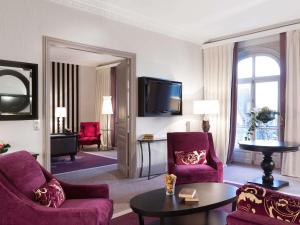 a living room with purple furniture and a flat screen tv at Le Grand Hotel de Cabourg - MGallery Collection in Cabourg