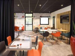 un restaurante con mesas y sillas y una gran ventana en ibis Nancy-Brabois en Vandoeuvre-lès-Nancy