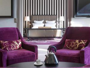 a hotel room with two chairs and a bed at Le Grand Hotel de Cabourg - MGallery Collection in Cabourg
