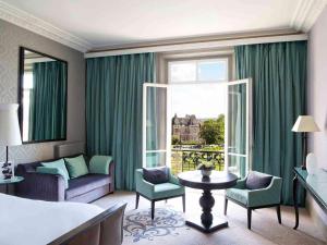a hotel room with a bed and a large window at Le Grand Hotel de Cabourg - MGallery Collection in Cabourg