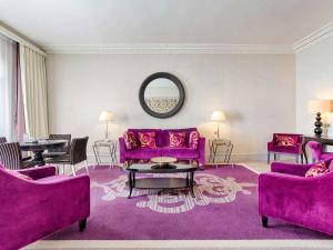 a living room with purple furniture and a mirror at Le Grand Hotel de Cabourg - MGallery Collection in Cabourg