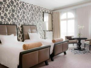 a hotel room with two beds and a table at Le Grand Hotel de Cabourg - MGallery Collection in Cabourg