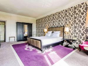 a bedroom with a large bed and a purple rug at Le Grand Hotel de Cabourg - MGallery Collection in Cabourg