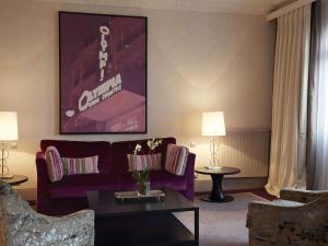 a living room with a purple couch and a table at Le Grand Hotel de Cabourg - MGallery Collection in Cabourg