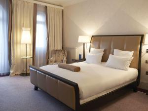 a bedroom with a large bed with white pillows at Le Grand Hotel de Cabourg - MGallery Collection in Cabourg