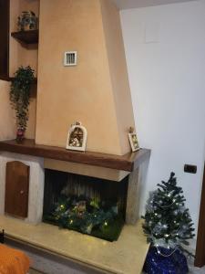 a christmas tree sitting in front of a fireplace at Appartamento Beatrice e Vioris in Pila