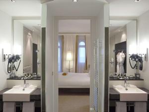 a bathroom with two sinks and a large mirror at Le Grand Hotel de Cabourg - MGallery Collection in Cabourg