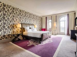 a bedroom with a large bed and a purple rug at Le Grand Hotel de Cabourg - MGallery Collection in Cabourg