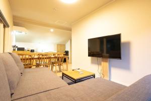 uma sala de estar com um sofá e uma televisão de ecrã plano em VILLA LOUISA em Furano