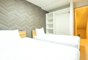 - 2 lits dans une chambre avec un mur dans l'établissement VILLA LOUISA, à Furano