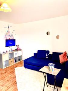 a living room with a blue couch and a tv at 5 Min from Disneyland cozy retreat in Montévrain