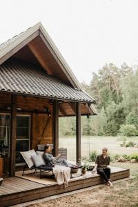 zwei Leute sitzen auf einer Veranda eines Hauses in der Unterkunft ALNUS KIEMAS in Kampiškiai