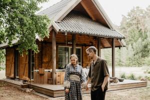 a man and a woman standing in front of a tiny house at ALNUS KIEMAS in Kampiškiai