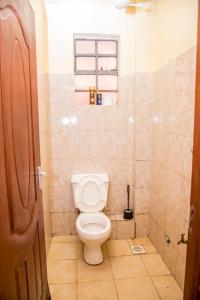 a small bathroom with a toilet and a window at Elnara Suites in Machakos