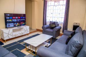uma sala de estar com sofás e uma televisão de ecrã plano em Elnara Suites em Masaku