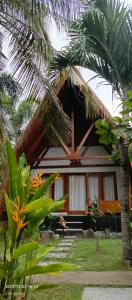 a house with a palm tree in front of it at Mengalung Bungalow in Kuta Lombok