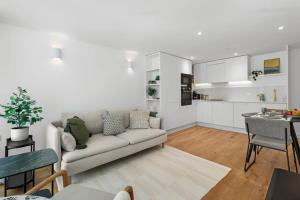 een witte woonkamer met een bank en een keuken bij Cool Apartment Close to Eastbourne Town Centre in Eastbourne