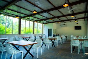 a dining room with tables and chairs and windows at The Green Jungle Resort in Karjat