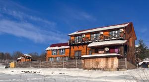 een groot houten huis met sneeuw op de grond bij Belvedere-Karpaty-Panorama in Skhidnitsa