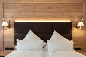 a bed with two white pillows and two lights above it at Hotel & Chalets Lampllehen in Marktschellenberg