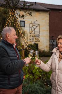 Ein Mann und eine Frau mit Weingläsern. in der Unterkunft Carré Hotel Zuid-Limburg in Hulsberg